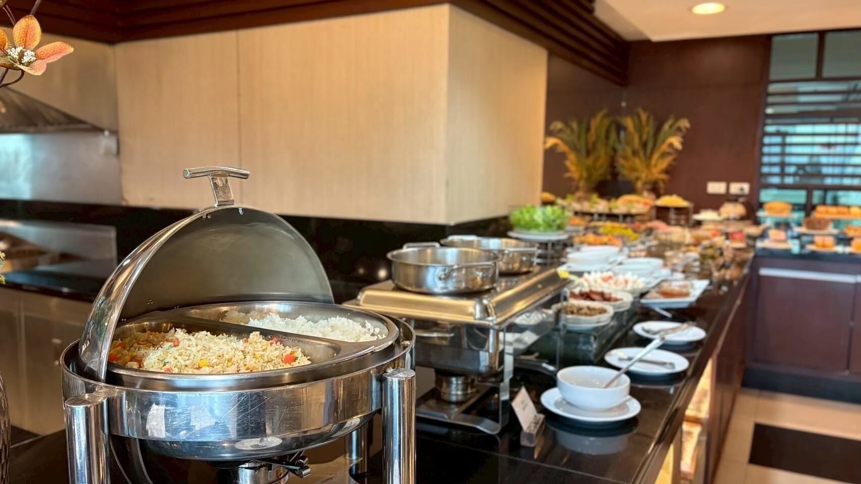 A buffet setup with various food items and a large pot of rice in the foreground.