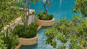 A pool area with clear blue water, surrounded by planters with various green plants. - Tara Mantra Cha Am Resort (Cha-am)