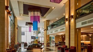 A spacious lobby with a central seating area, a reception desk, and a high ceiling with hanging light fixtures. - Tara Mantra Cha Am Resort (Cha-am)