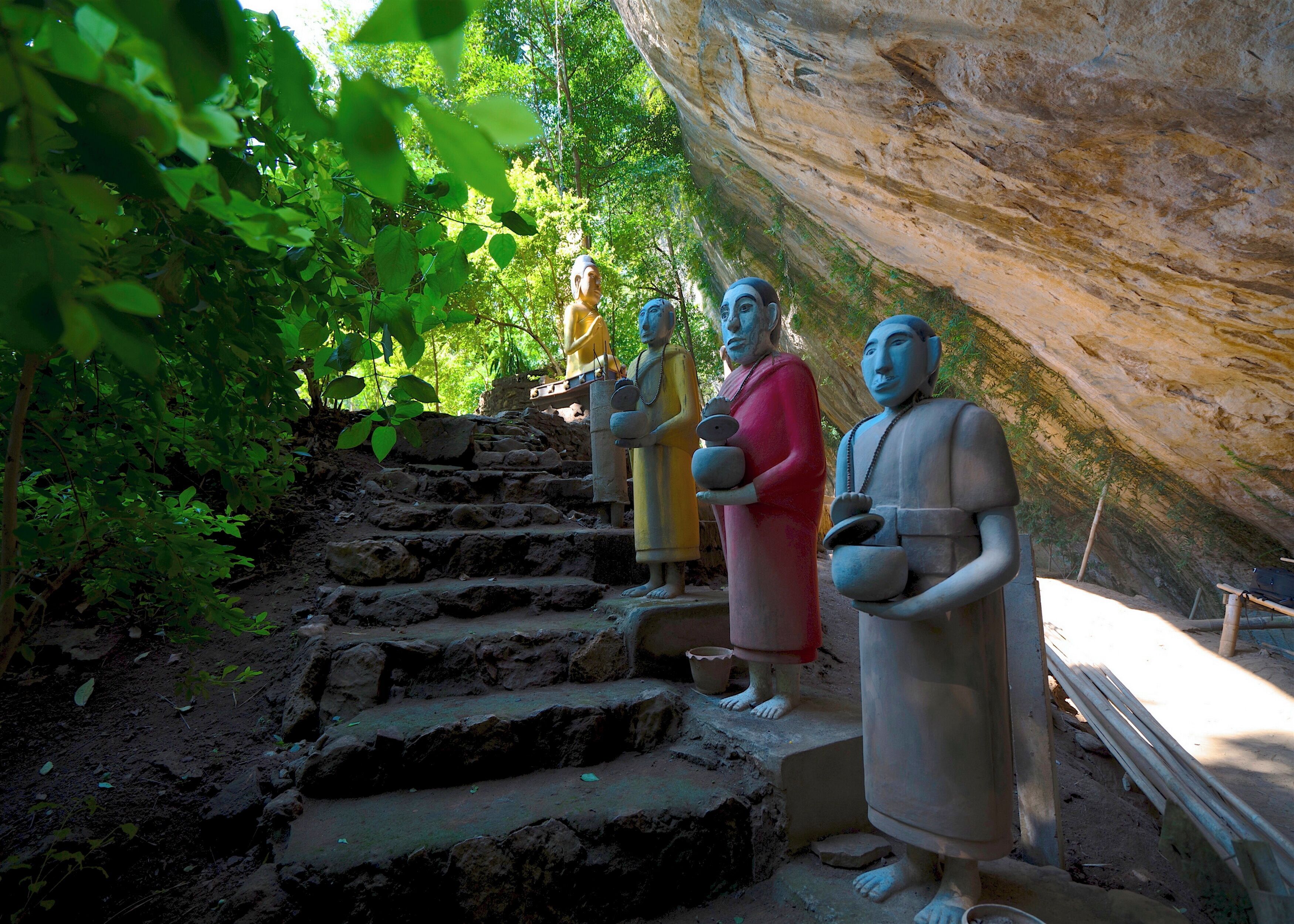 Un conjunto de escalones de piedra que conducen a un acantilado con estatuas de figuras con vestimenta tradicional.