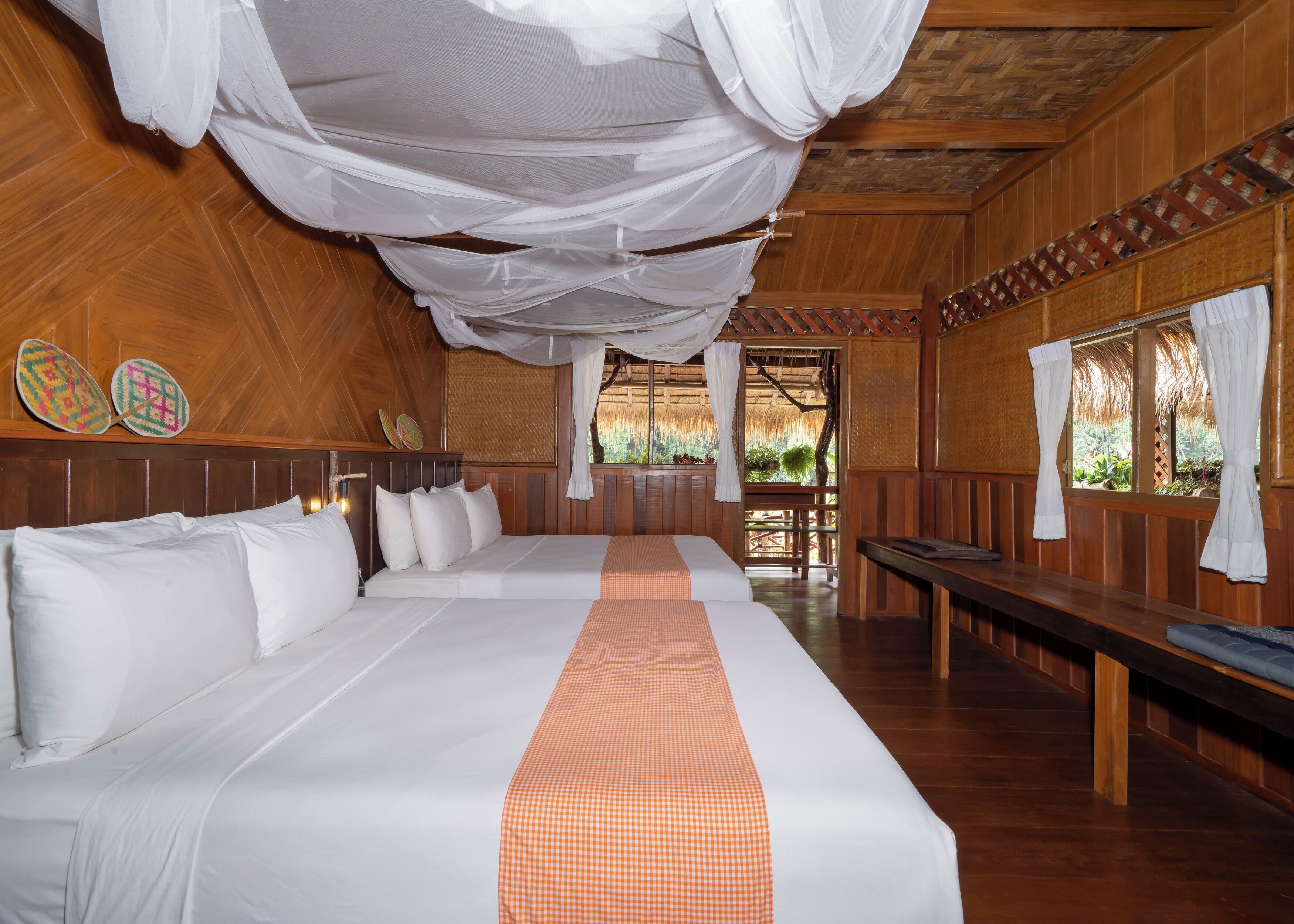 A large bed with a white and orange checkered bedspread, wooden walls, and a canopy.