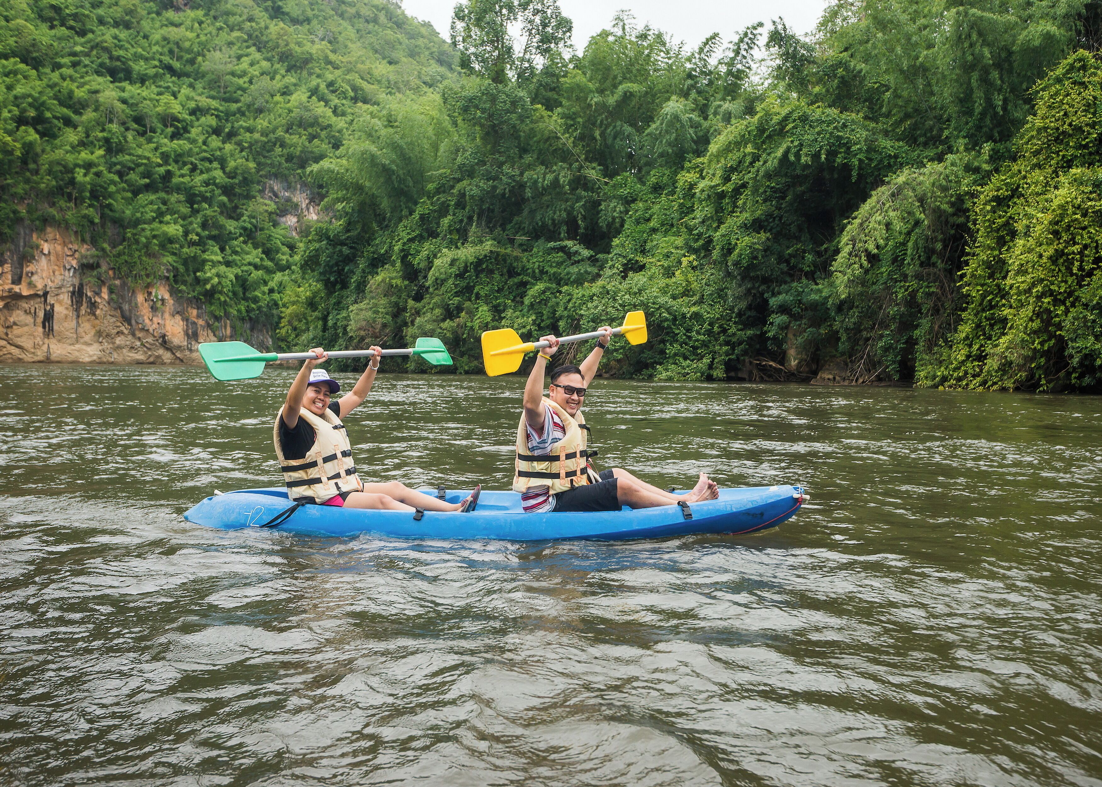 Dos personas haciendo kayak en un río rodeado de vegetación densa.