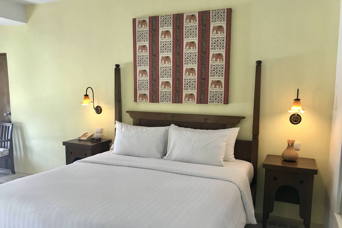 A neatly made bed with white linens, a wooden headboard, and two bedside tables with lamps.