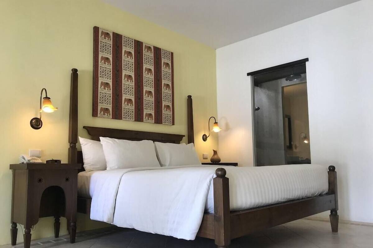 A bed with a wooden frame, two bedside tables, a wall-mounted light fixture, and a mirror.