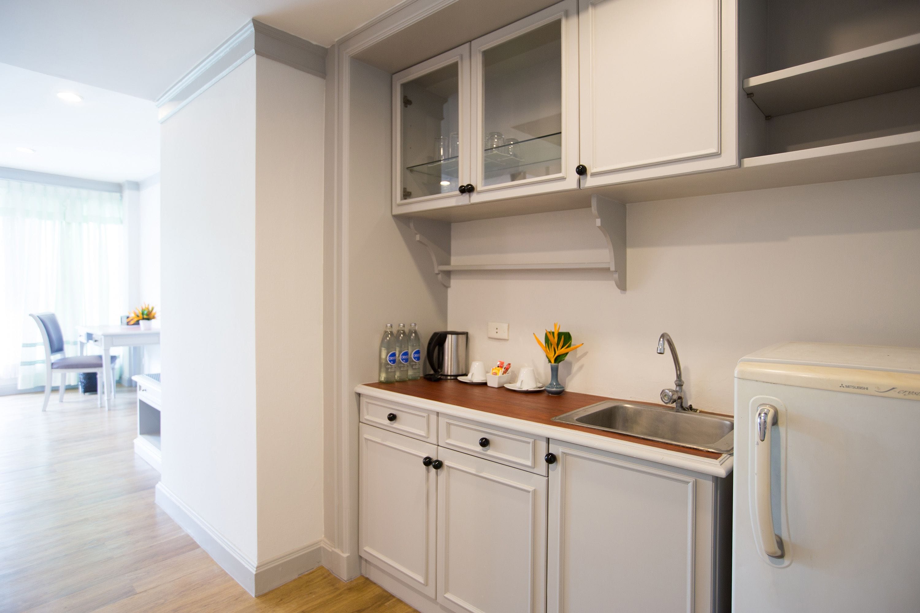 A modern kitchen with white cabinetry, a wooden countertop, and a built-in refrigerator.