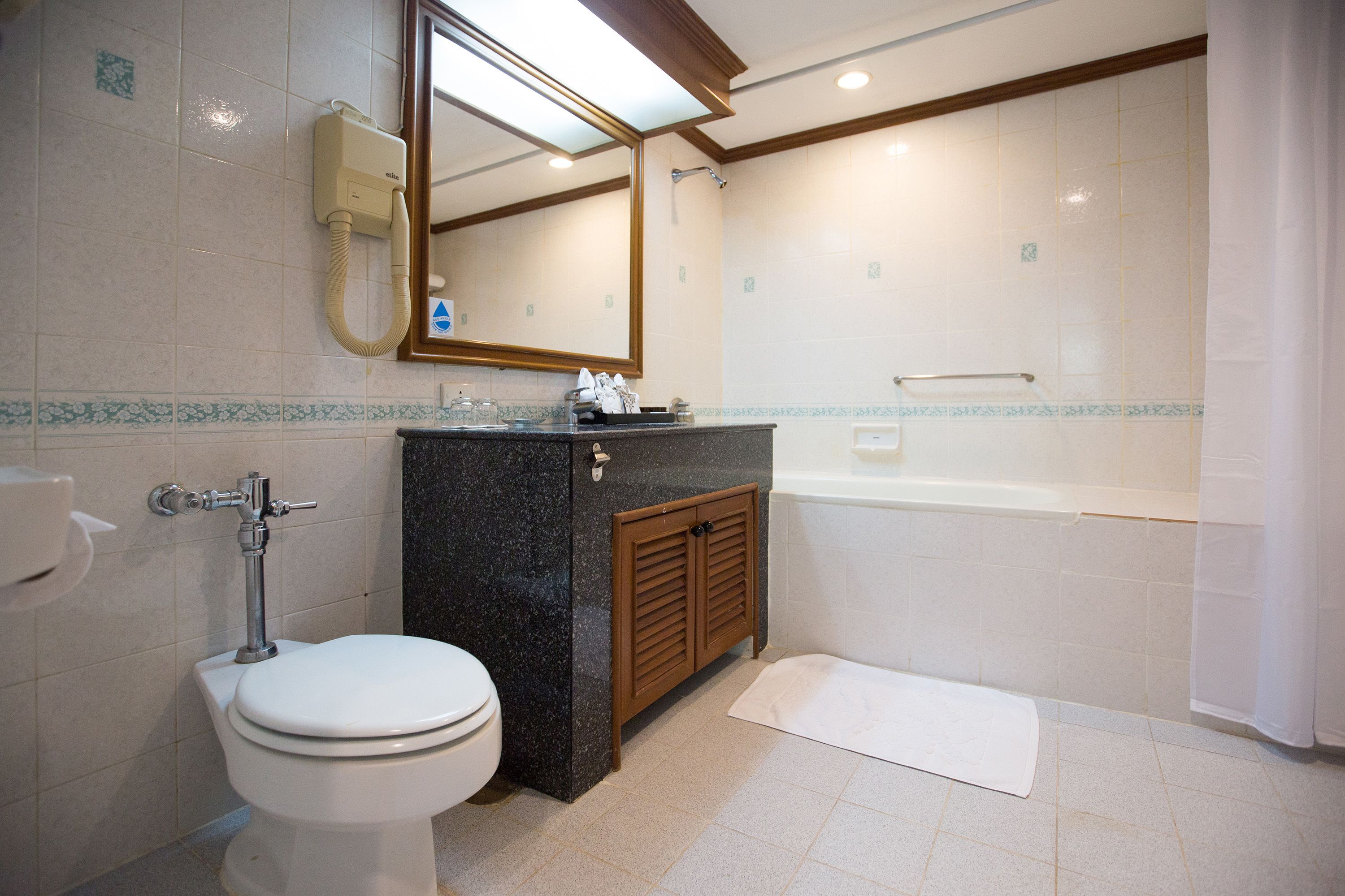 A bathroom with a toilet, sink, mirror, and bathtub.