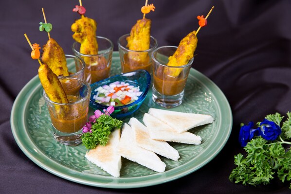 A plate with skewers of grilled food, a bowl of diced vegetables, and slices of bread.