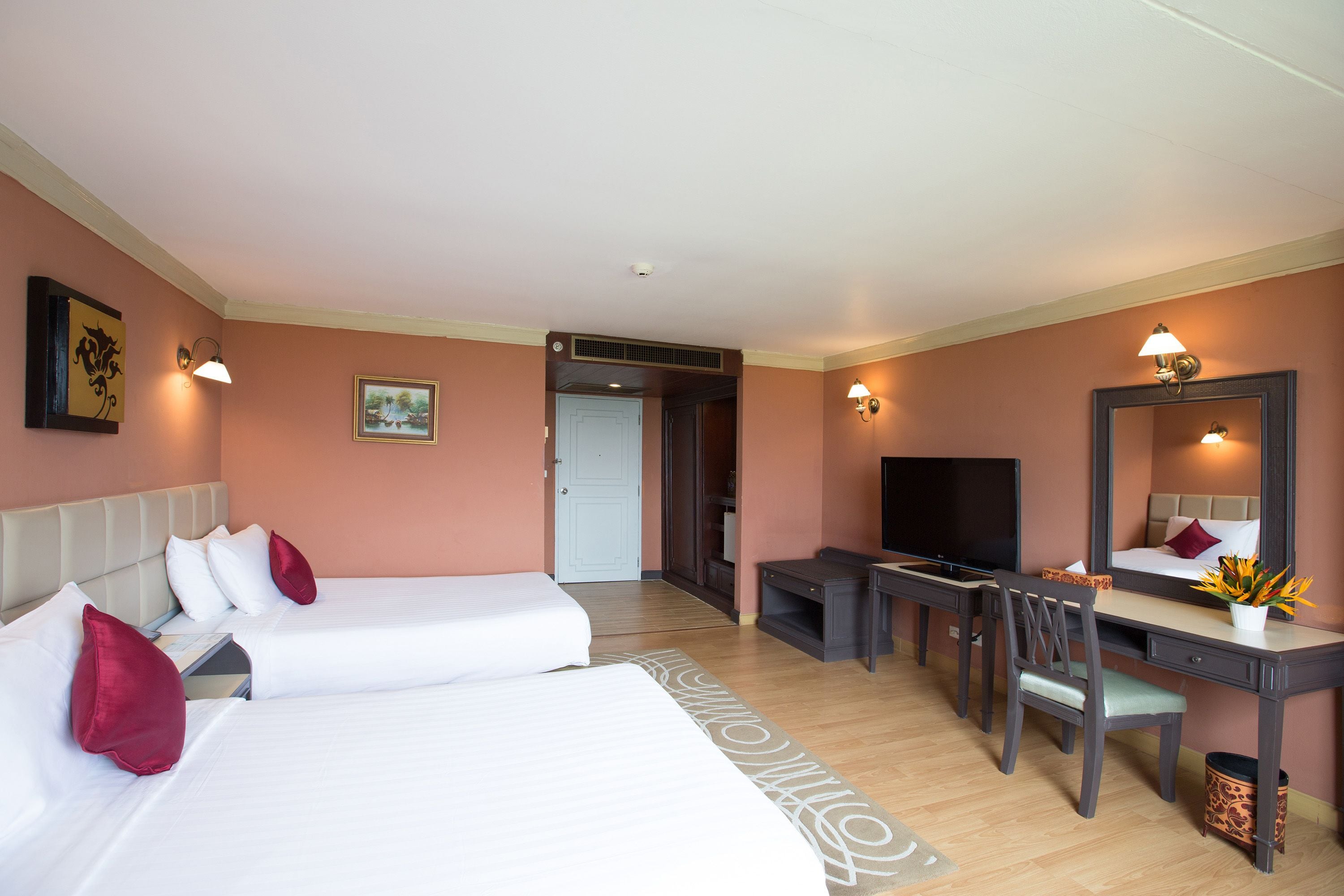 A hotel room with two beds, a desk, a chair, a TV, and a mirror.