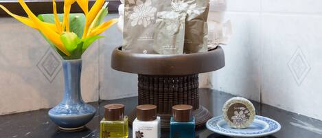 A bathroom with a blue vase, a soap dish, and three bottles of body lotion.