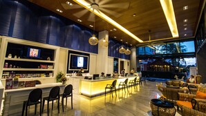 A modern lobby with a reception desk, bar area, seating, and a pool view. - The Beach Boutique House (Karon)