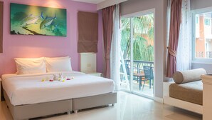 A hotel room with a bed, a painting, a balcony with a chair, and a view of greenery. - The Beach Boutique House (Karon)