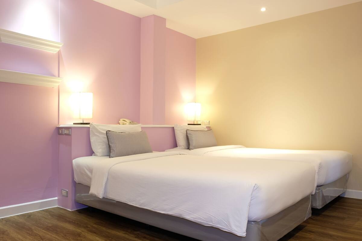 A double bed with white bedding, two bedside lamps, and a nightstand with a phone.