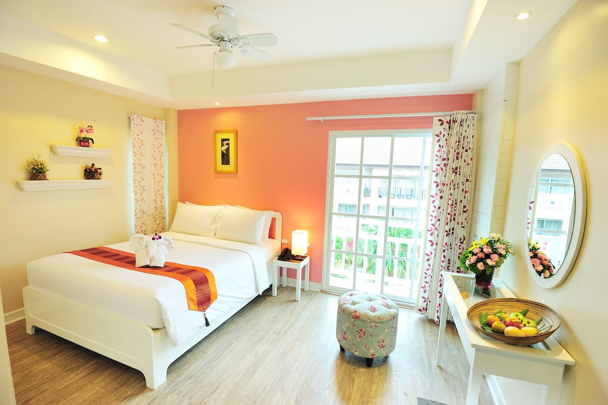 A hotel room with a bed, bedside table, nightstand, and a window with curtains.