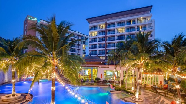 A hotel with a swimming pool, palm trees, and string lights. - The Beach Boutique House (Karon)