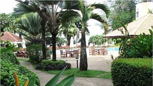 Un jardín con palmeras, un sendero y mobiliario exterior.