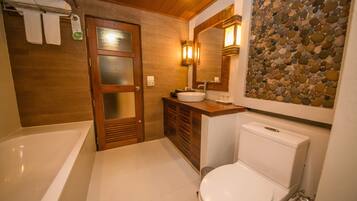 Un baño con bañera, inodoro, tocador con lavabo y espejo.