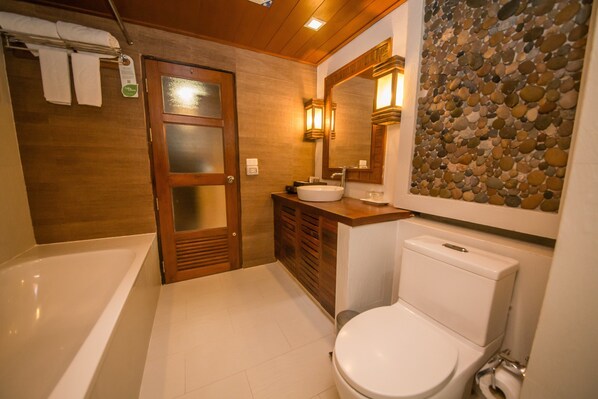 Un baño con bañera, inodoro, tocador con lavabo y espejo.