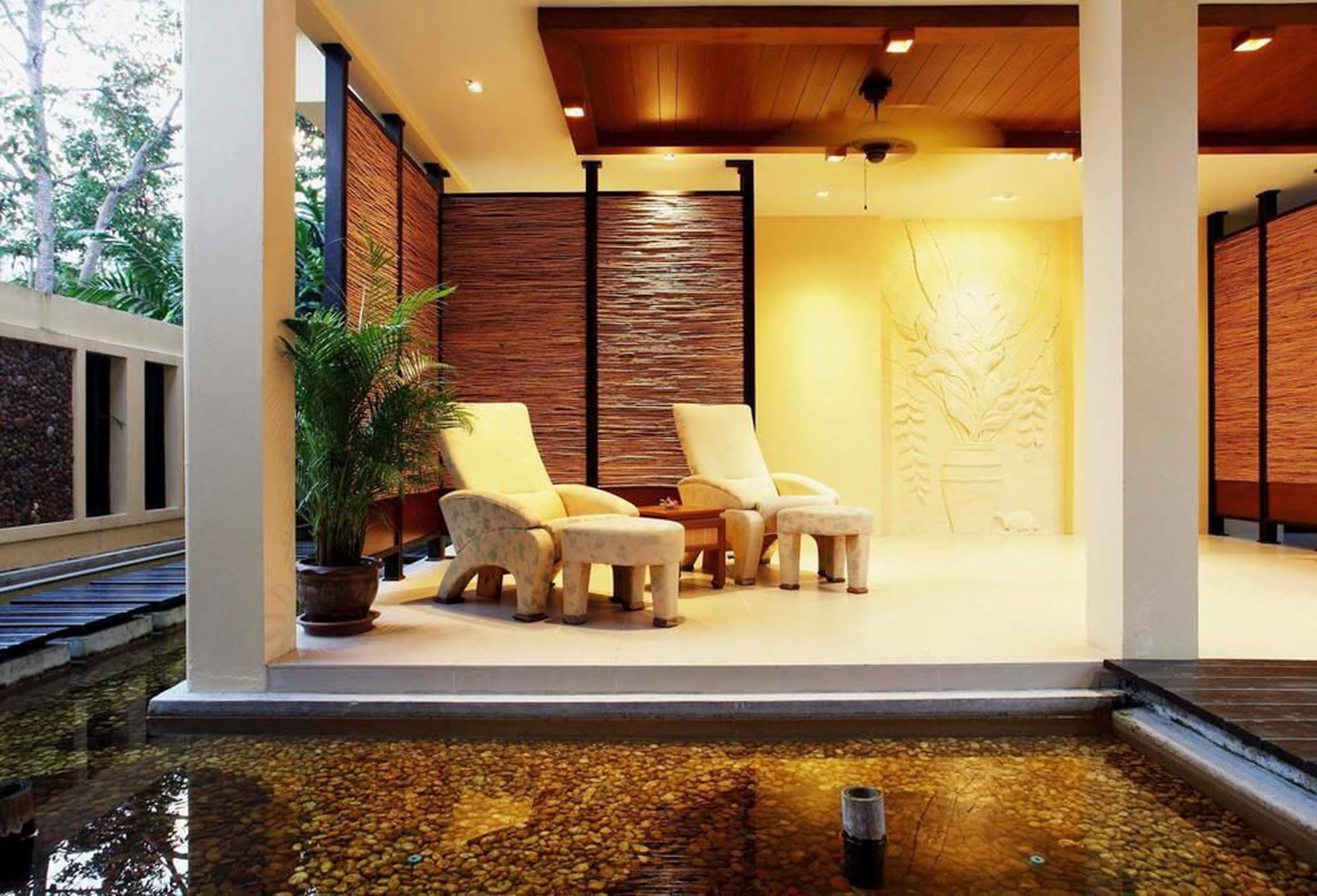 A modern indoor pool area with lounge chairs and a potted plant.