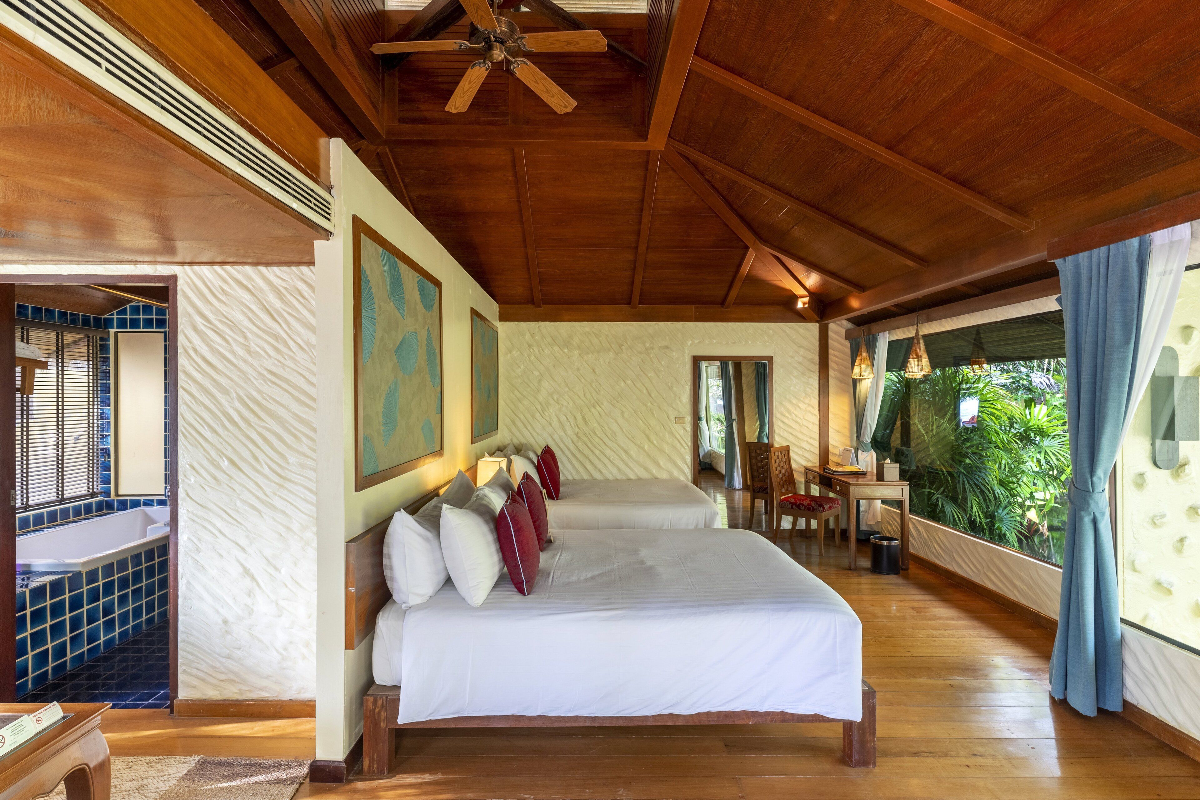 Amplia habitación con una cama grande, techo de madera y vistas al verdor.