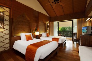 Two large beds with white linens and orange accents, a television, and a small table with a chair.