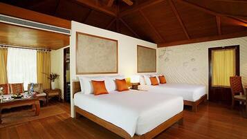 A hotel room with two beds, wooden flooring, a ceiling fan, and a large window with curtains.