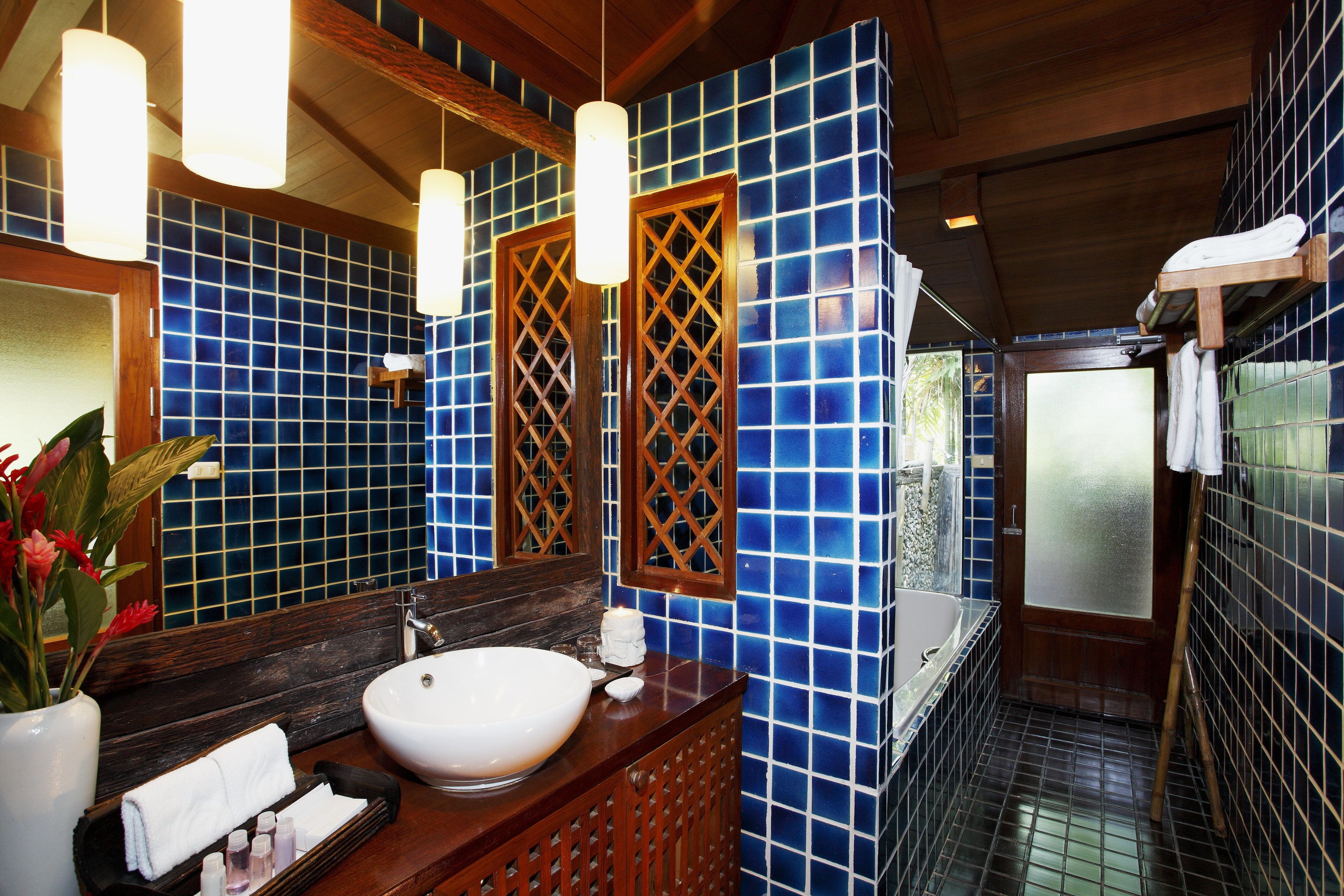 A bathroom with a wooden vanity, a white sink, and blue-tiled walls.