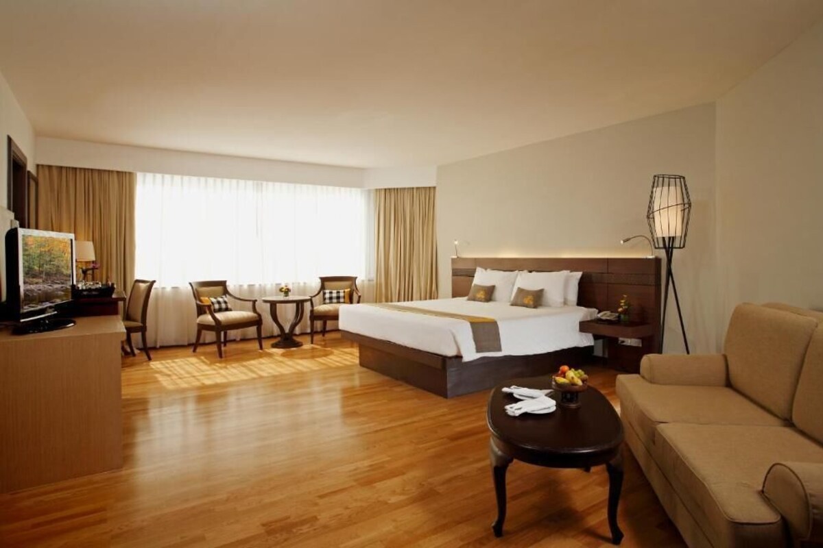 Une chambre d’hôtel avec un lit, un canapé, une télévision, un bureau et une lampe.