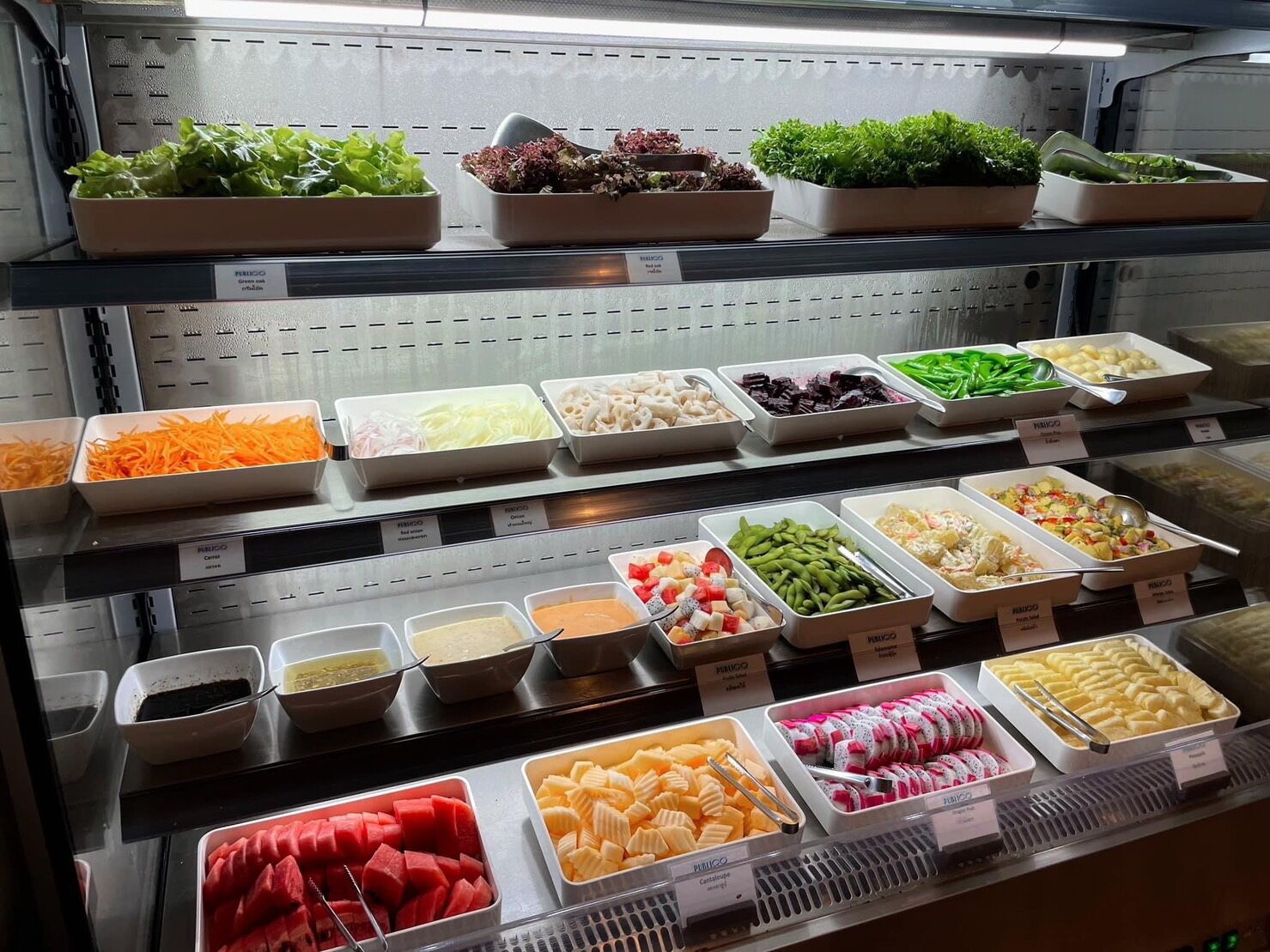 A buffet with various food options including salads, vegetables, and desserts.