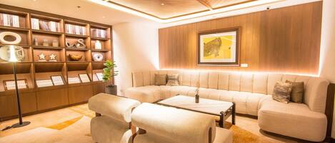 A modern living room with a sectional sofa, a coffee table, and a bookshelf.