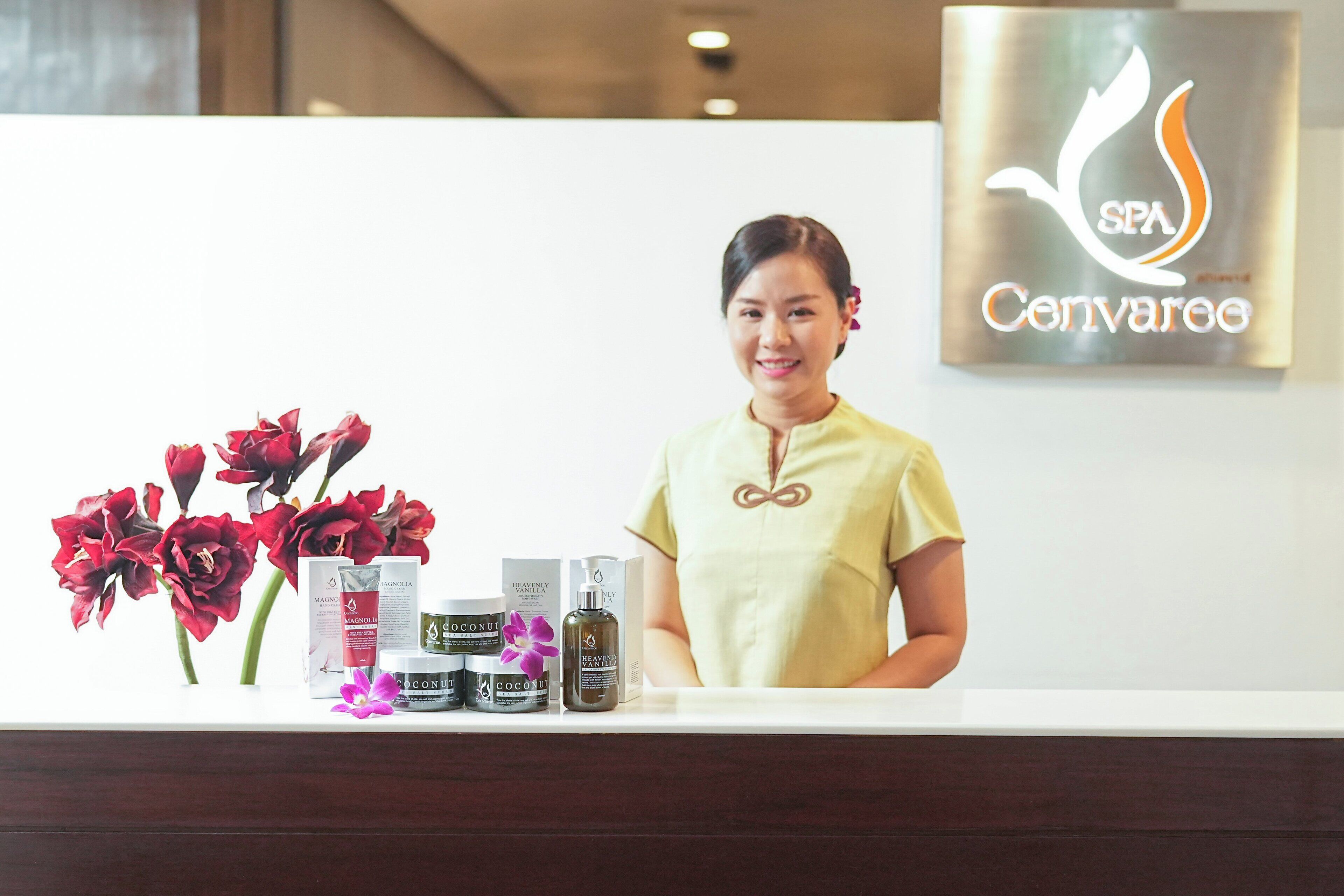 A reception desk with a woman standing behind it, displaying various spa products.