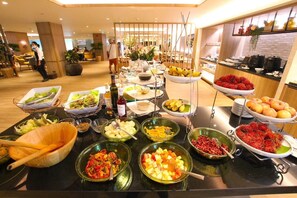 Ein Buffet mit verschiedenen Speisen, darunter Obst, Gemüse und Getränke.