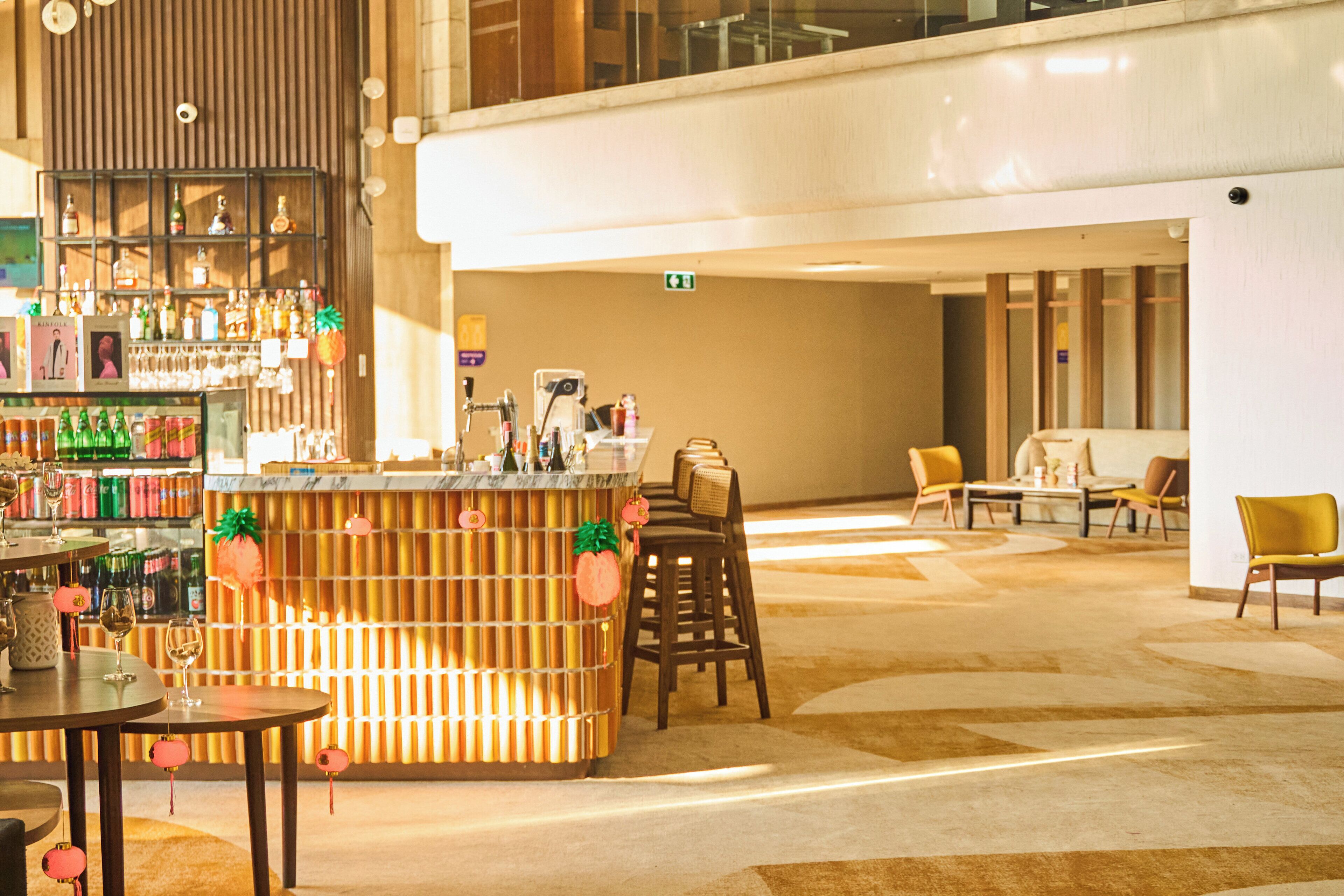 A bar area with a wooden counter, bar stools, and a variety of bottles and glasses.