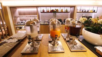A breakfast bar with three beverage dispensers, a coffee machine, and a large flower pot.