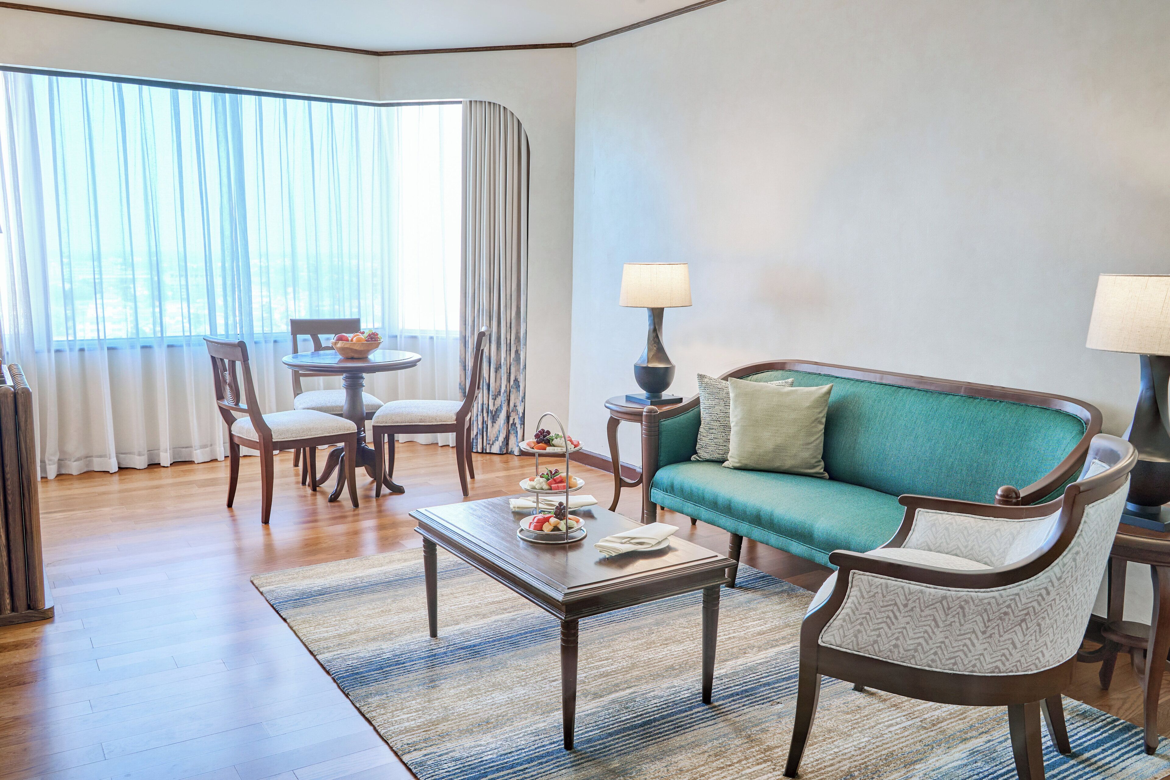 Un salon comprenant un canapé, des fauteuils, une table basse et une table d’appoint avec des lampes.