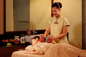 Um espaço de spa com uma mesa de massagem, uma pessoa recebendo massagem e um espelho refletindo o ambiente.