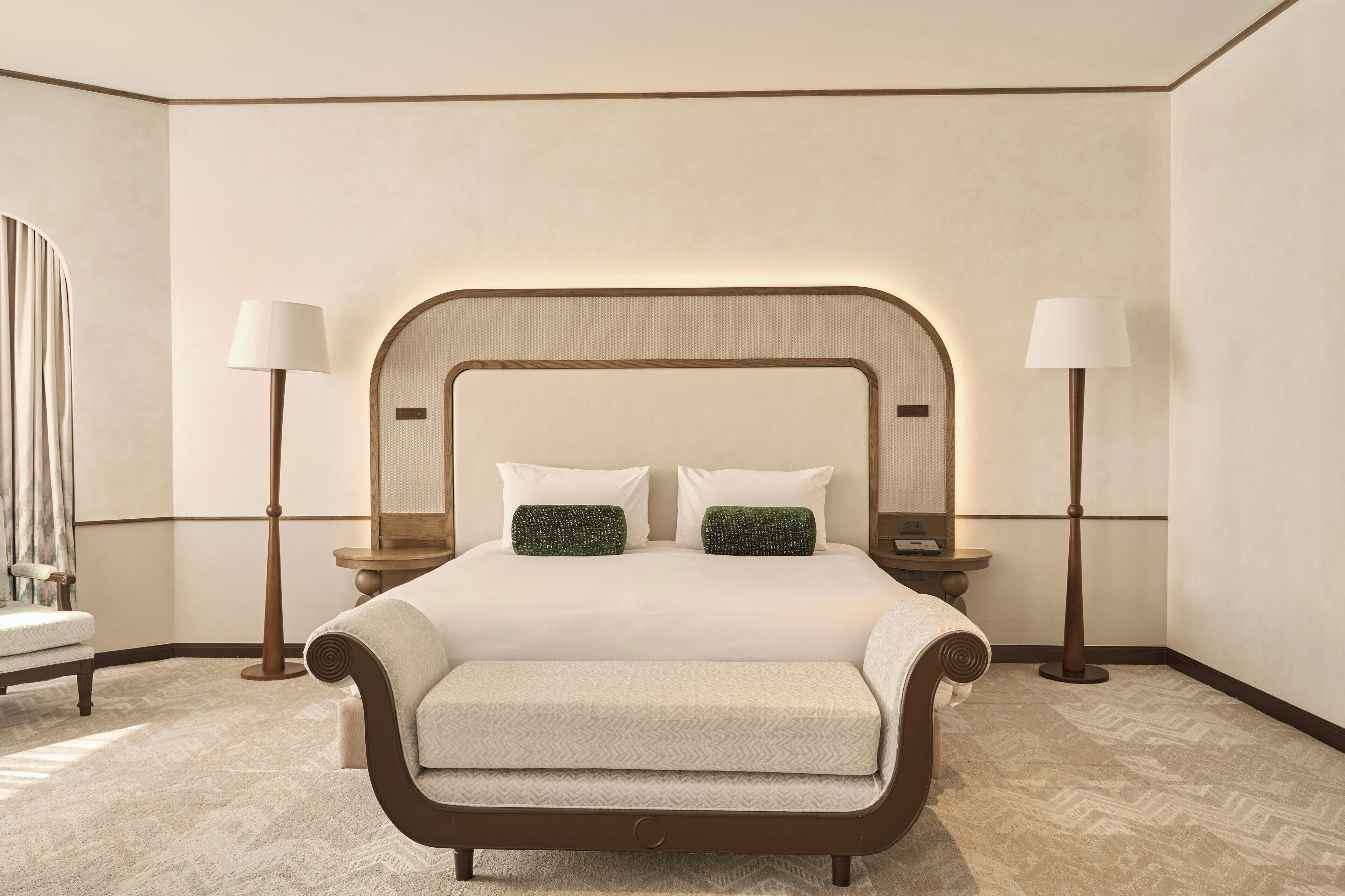 A neatly arranged bedroom with a large bed, two bedside tables, and a chair.