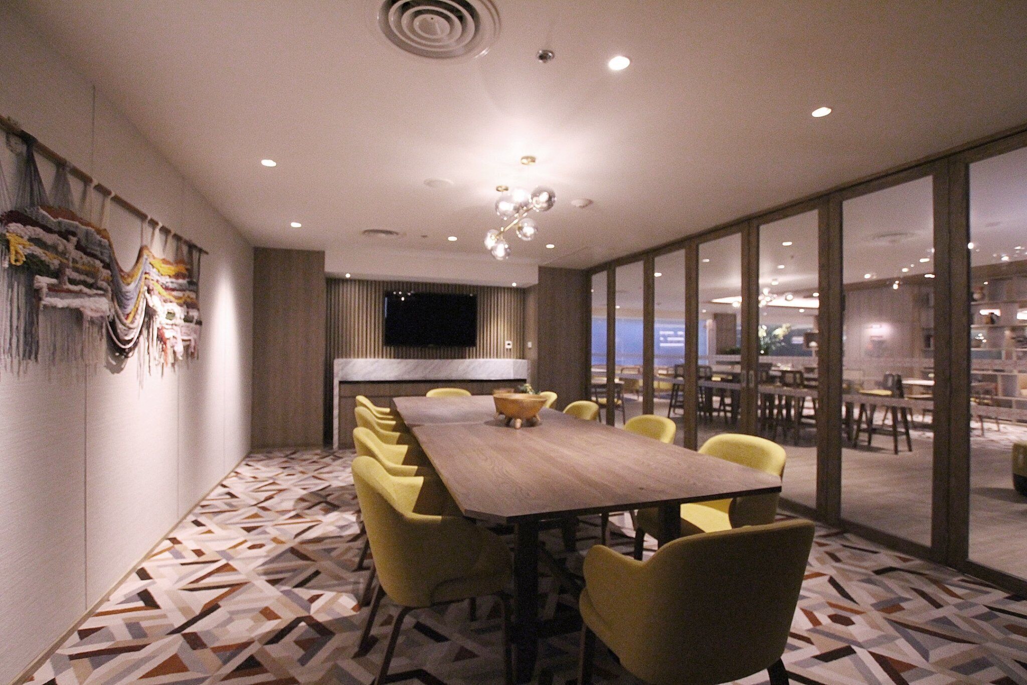 A conference room with a long table, yellow chairs, and a patterned floor.