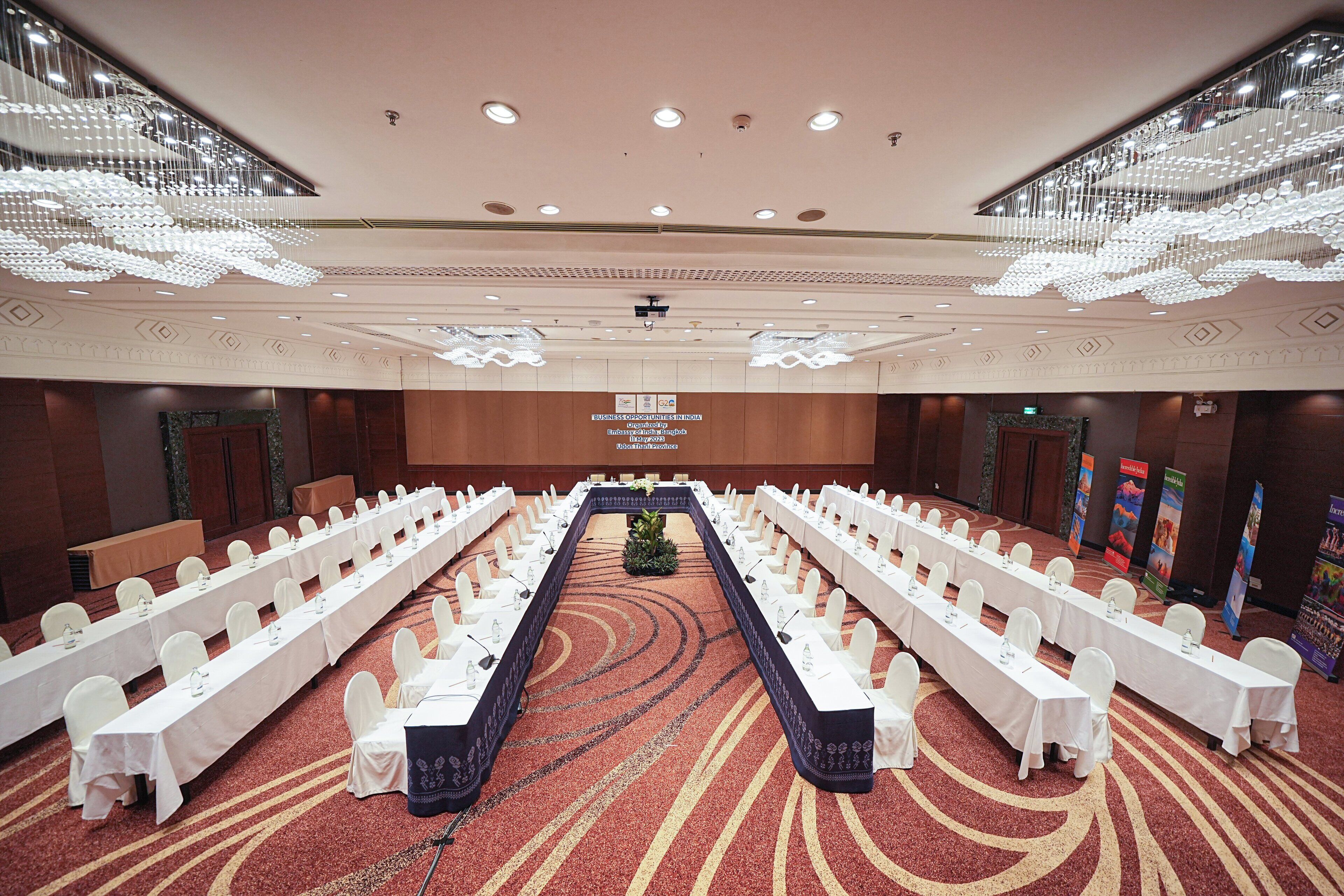 A conference room with long tables, white chairs, and a central aisle.