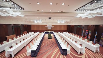A conference room with long tables, white chairs, and a central aisle.