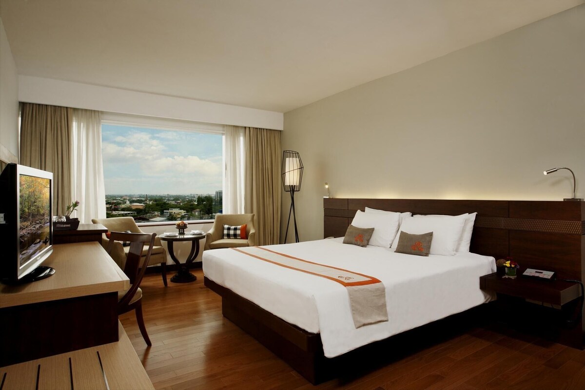 Une chambre d’hôtel avec un lit, un bureau, une chaise et une vue sur la ville.