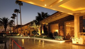 A hotel with a covered outdoor area, palm trees, and a brick facade. - Holiday Inn Al Khobar - Corniche by IHG (Al Khobar)