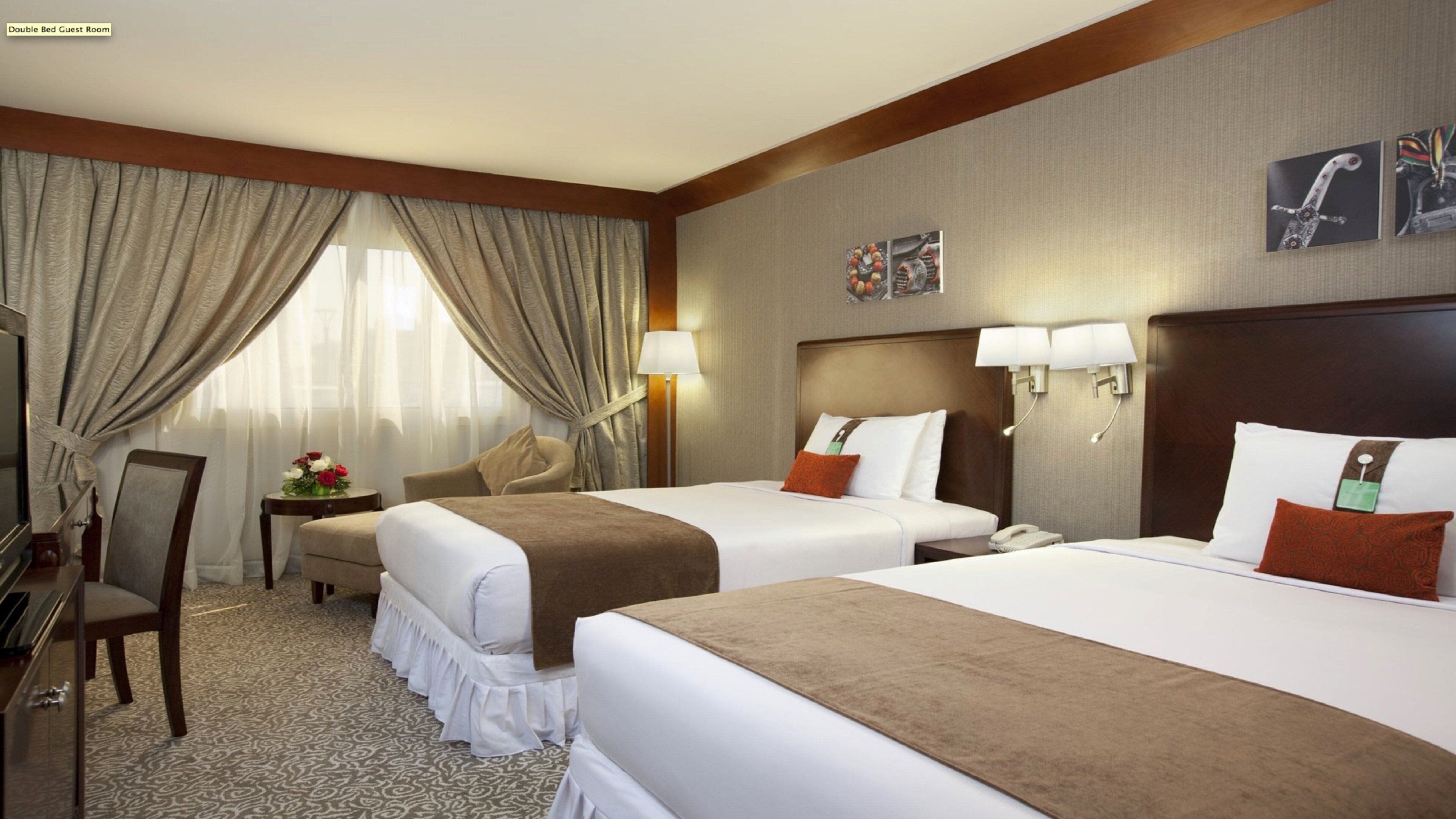 Quarto de hóspedes com cama de casal e duas camas, uma escrivaninha, uma cadeira e um abajur.