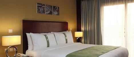 Habitación de hotel con cama, dos lámparas de noche, teléfono y una obra de arte en la pared.
