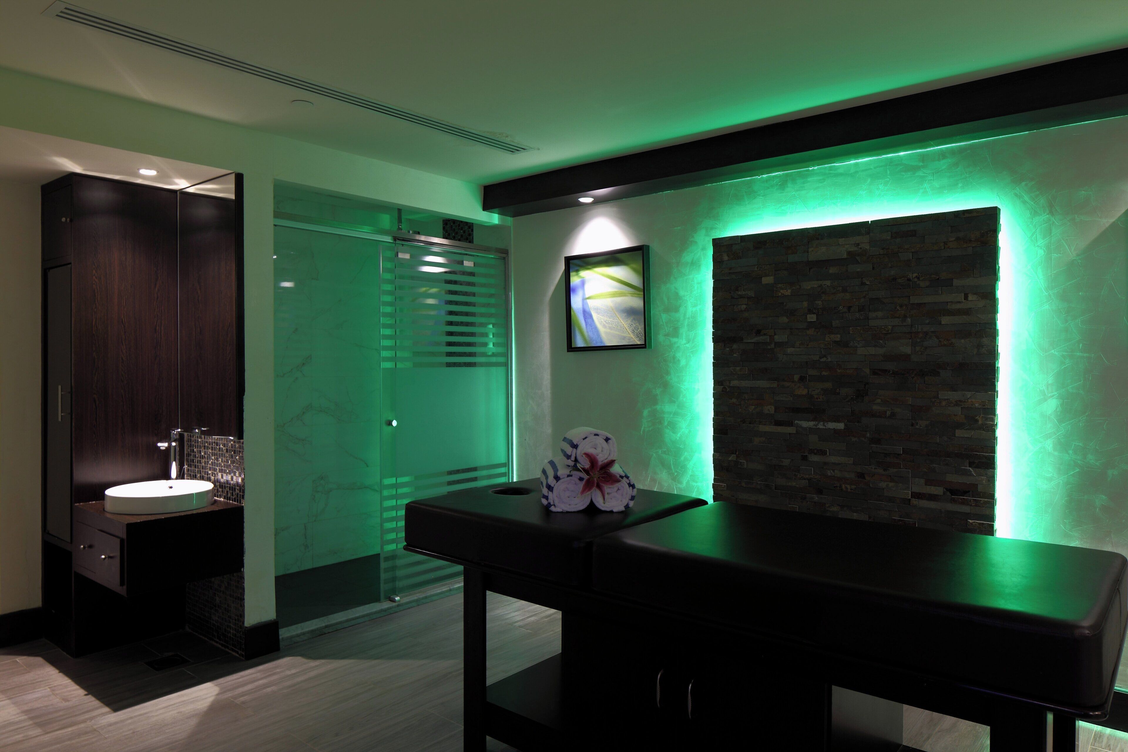 A modern bathroom with a marble sink, a glass shower enclosure, and a stone accent wall.