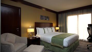 Una habitación de hotel con una cama grande, un sofá, un escritorio con lámpara y una silla.