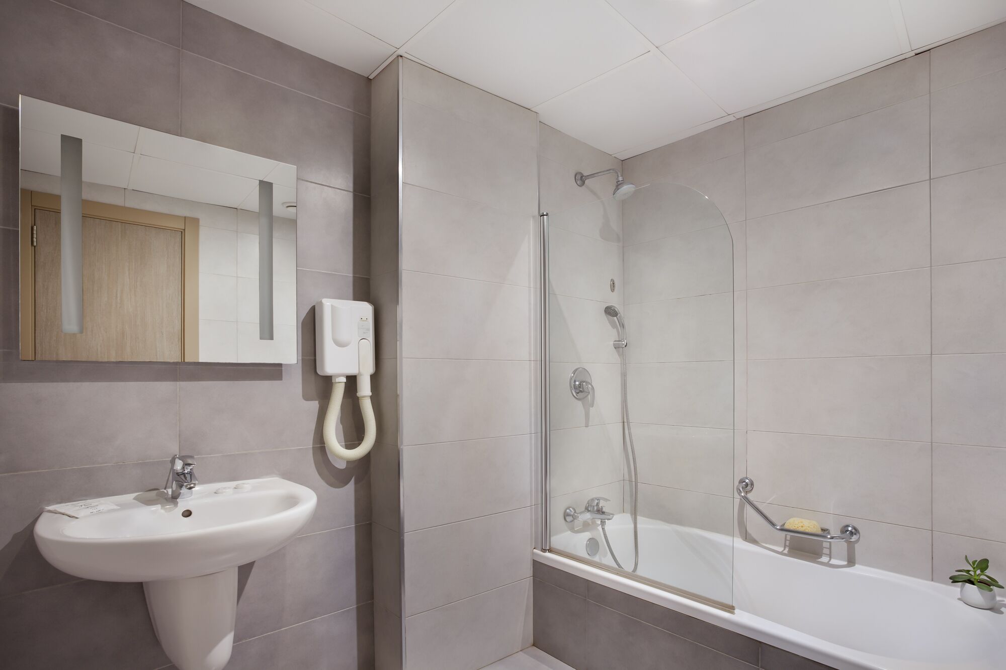 A modern bathroom with a sink, mirror, shower, and bathtub.