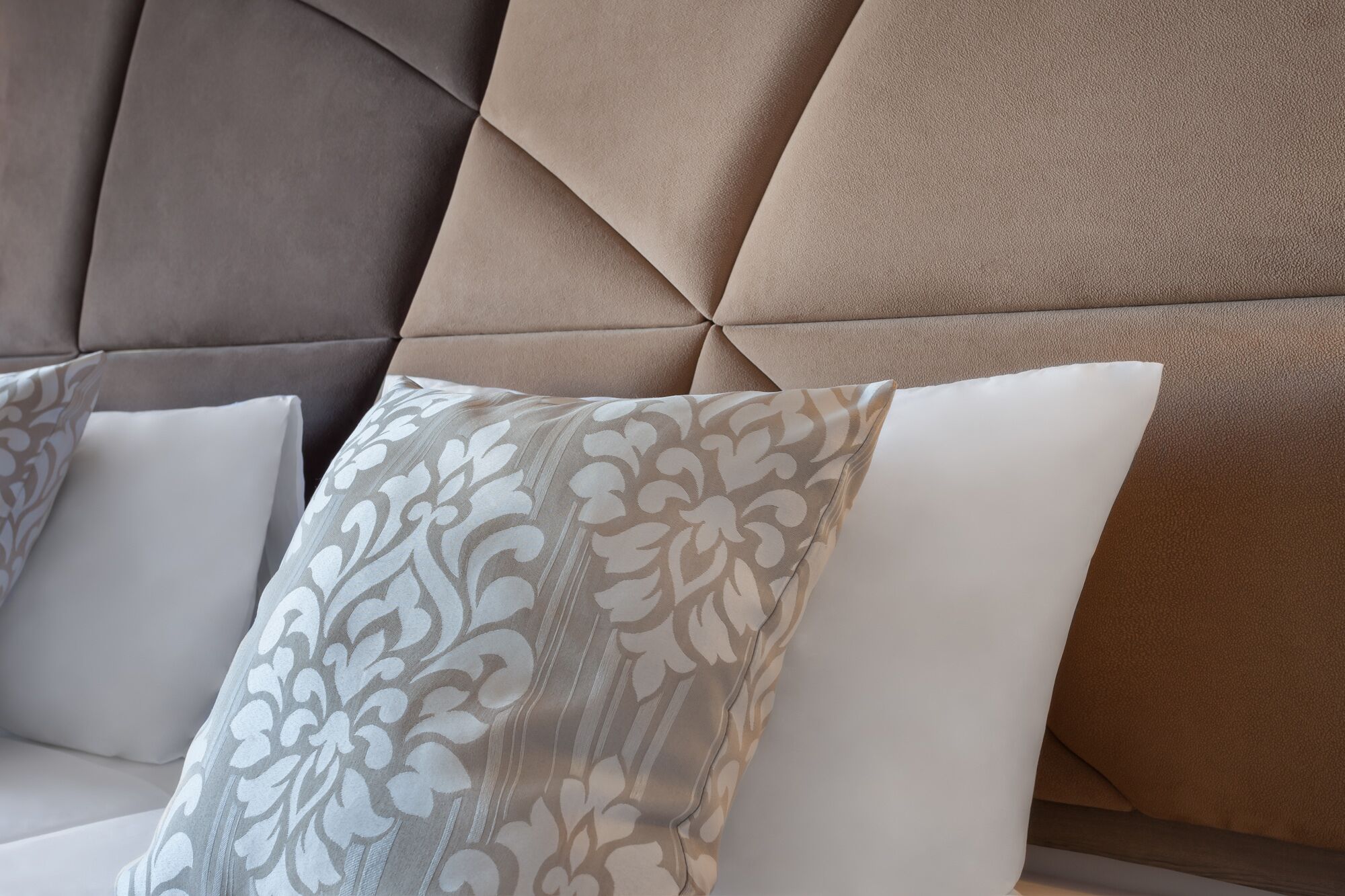 Une partie d’un canapé, avec un coussin à motifs et un coussin uni.