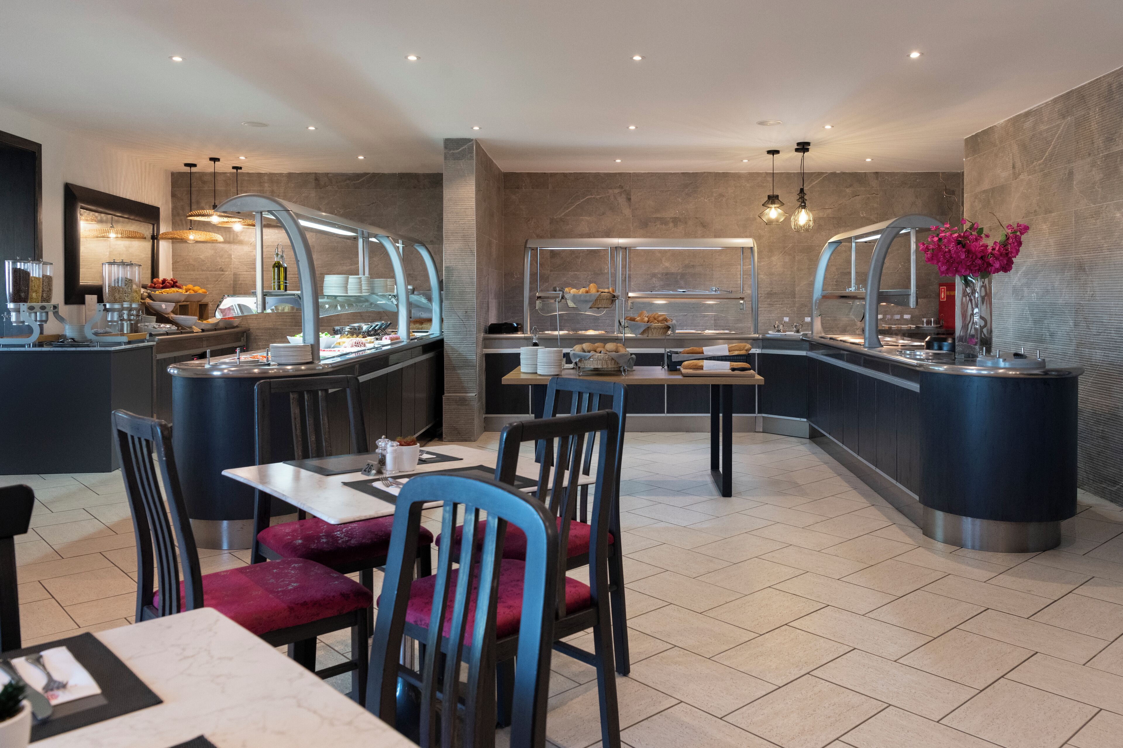 A modern breakfast area with a buffet, seating, and a bar.