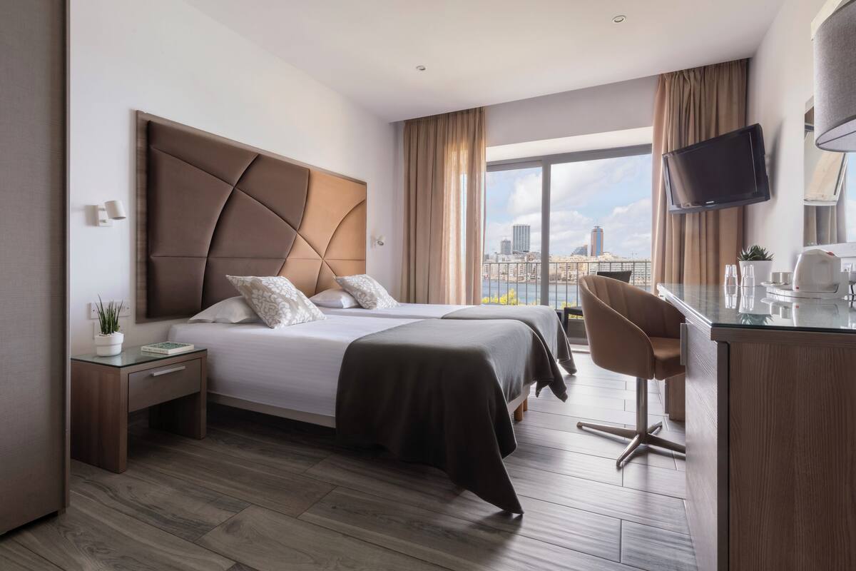 A modern hotel room with a large bed, a desk, and a TV.