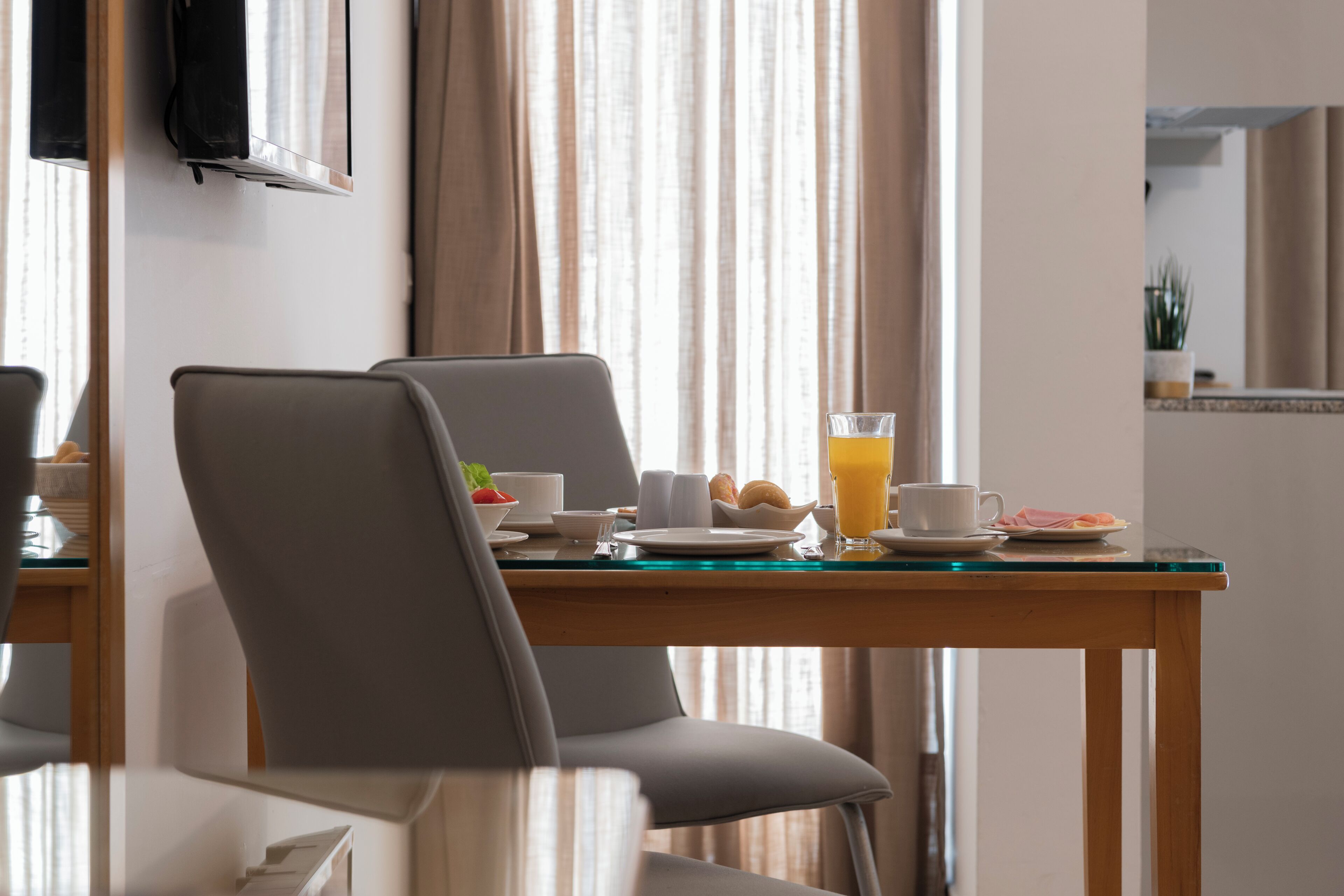 Une chambre d’hôtel avec une table de petit-déjeuner mise, comprenant des assiettes, des tasses et un verre de jus d’orange.